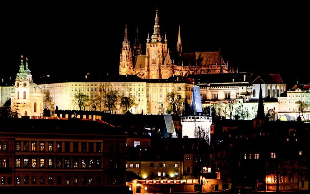 La ciudad capital de Praga en la noche mirando hacia el castillo desde un puente sobre el río